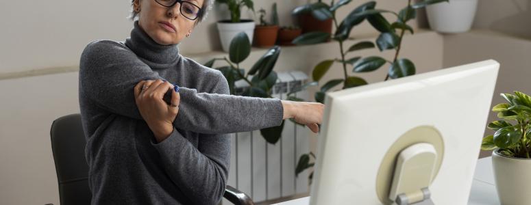Personne souffrant de douleurs au bras devant son écran